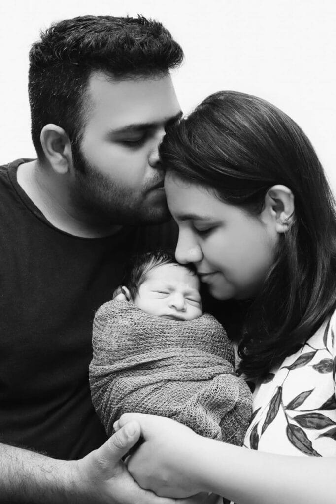 Parents holding and kissing their newborn baby