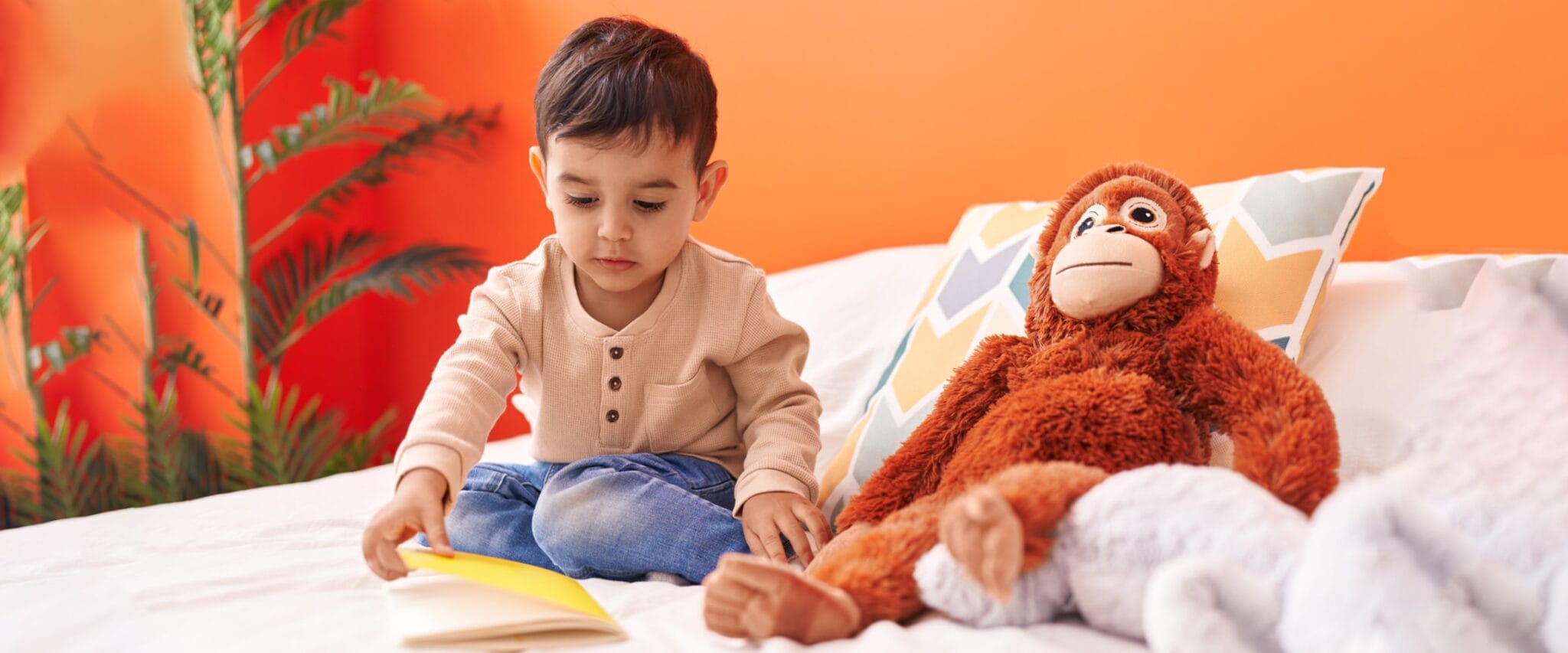 Toddler reading a book with a stuffed monkey