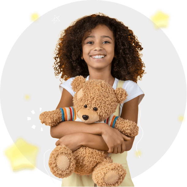 A smiling girl holding a teddy bear.