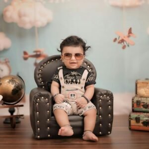 Baby wearing sunglasses sitting in a chair with a travel themed background.