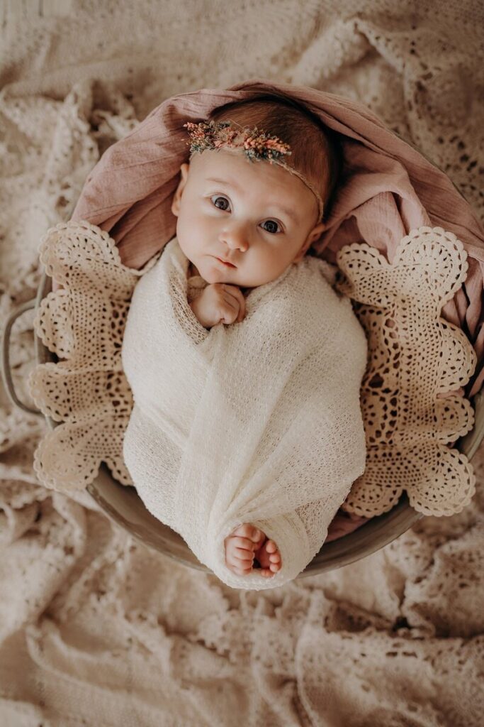 A baby wrapped in a blanket wearing a small flower headband