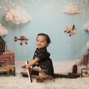 Smiling baby on a wooden toy airplane in a vintage travel themed setup