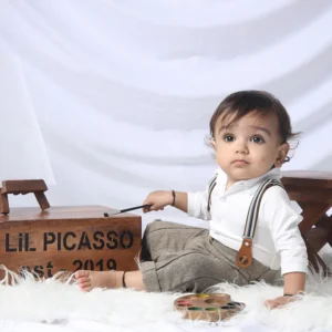 Baby holding a paintbrush beside a wooden_Lil Picasso box