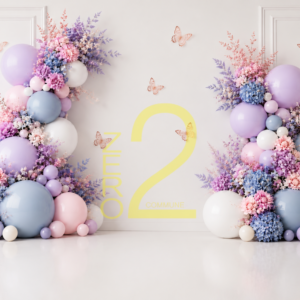 Pastel baby girl photography backdrop with lavender, pink and blue balloons, floral arrangements, butterflies and cream paneled wall