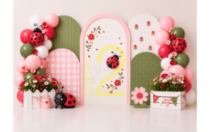 Baby girl ladybug theme photography backdrop with pink and green arches, flowers, balloons and cute ladybug decorations