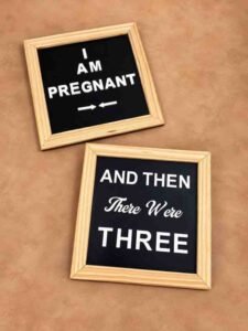 Pregnancy announcement photography props with black letter boards, wooden frames, and white messages reading “I Am Pregnant” and “And Then There Were Three.”