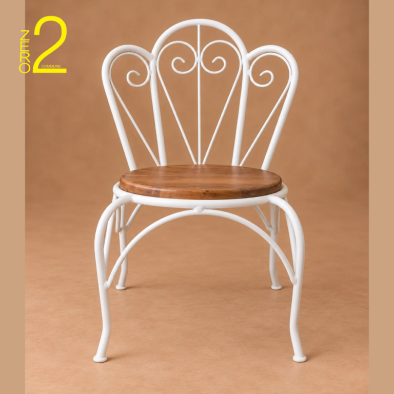 White metal photography chair with decorative scrollwork backrest, curved legs, and a round brown wooden seat.