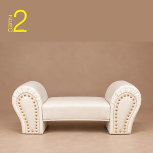 White upholstered baby photography sofa with curved armrests and gold-tone decorative studs